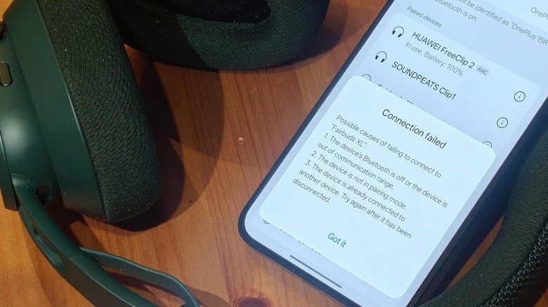 A smartphone leaning on headphones, with a failed connection message.