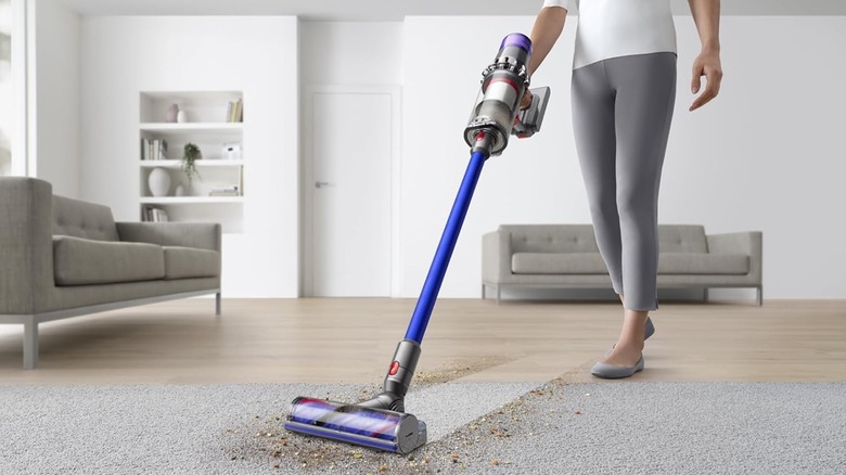 A person using the Dyson V11 cordless vacuum to clean the floor.