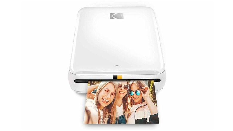 Kodak Step Instant portable printer seen printing an image of a group of friends.
