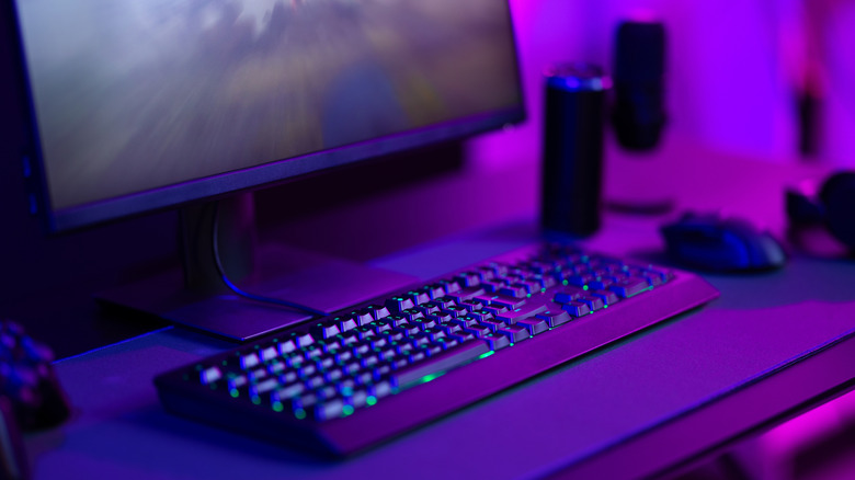 PC and keyboard in purple light on desk