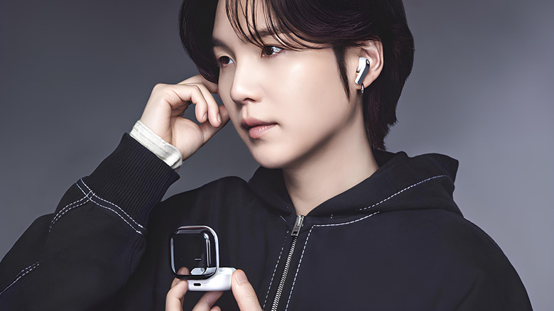 Woman wearing a pair of white galaxy buds with shiny case open in hand