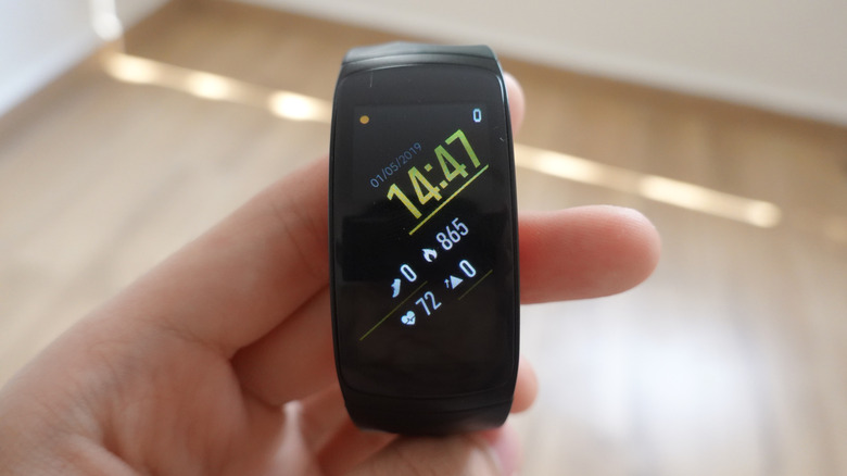 A user holds a black Galaxy Fit 2 Pro in their left hand