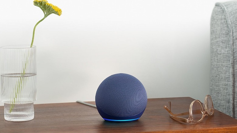 Amazon Echo Dot placed on a wooden table alongside vase and glasses