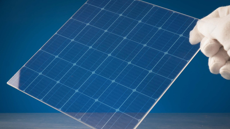 Transparent solar glass held up by a gloved hand