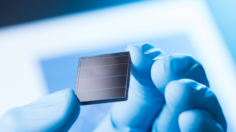 A gloved hand holding up a small prototype solar cell