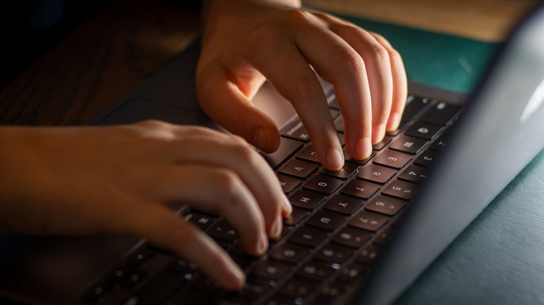 A person typing on a laptop keyboard