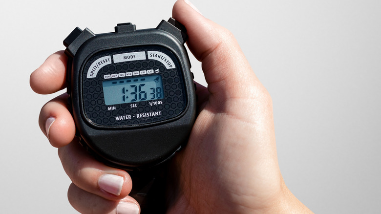 A person holding a stopwatch, clicking the timer on the side