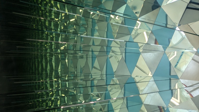 Woman wearing green shirt looking at herself in mirror