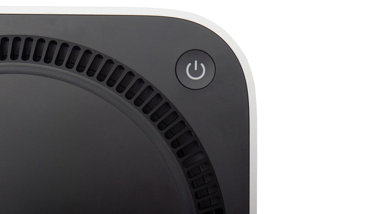 Bottom of an Apple Mac Mini showing its power button, on a white background.