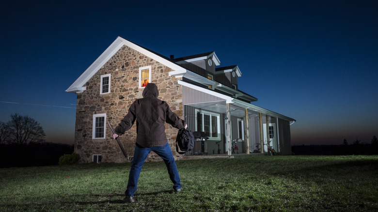 A man standing still on a ground in front of a house