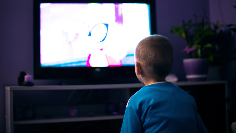 A small child staring at a bright television screen.