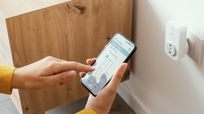 A person setting up a smart plug through a smartphone.