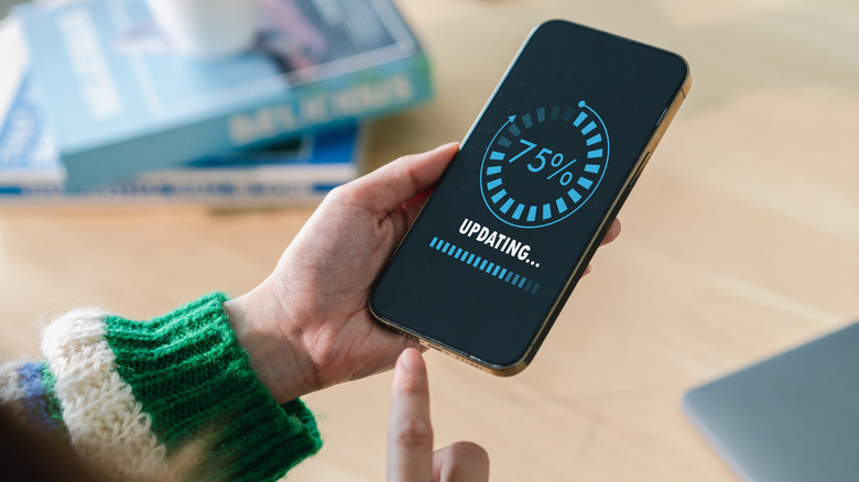 A person holding a smartphone with an updating screen.