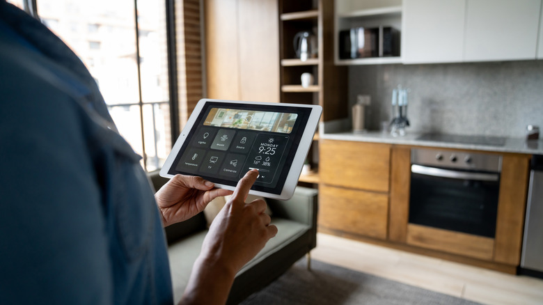 A person using a tablet to access smart home devices.