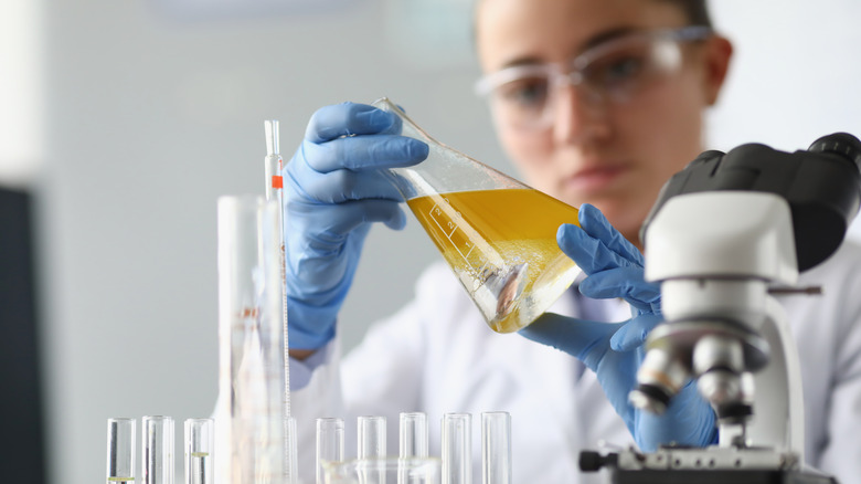 Woman chemist holds flask with yellow liquid