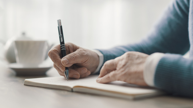 Woman sitting at a desk writing a note in a book