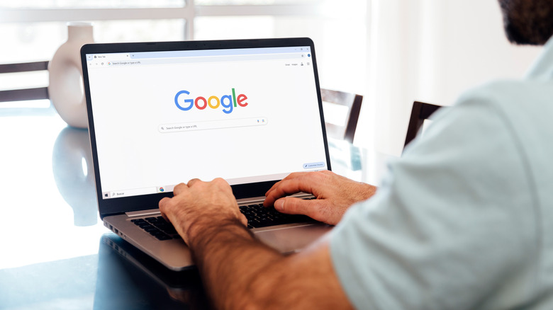 Man typing into Google search on a laptop