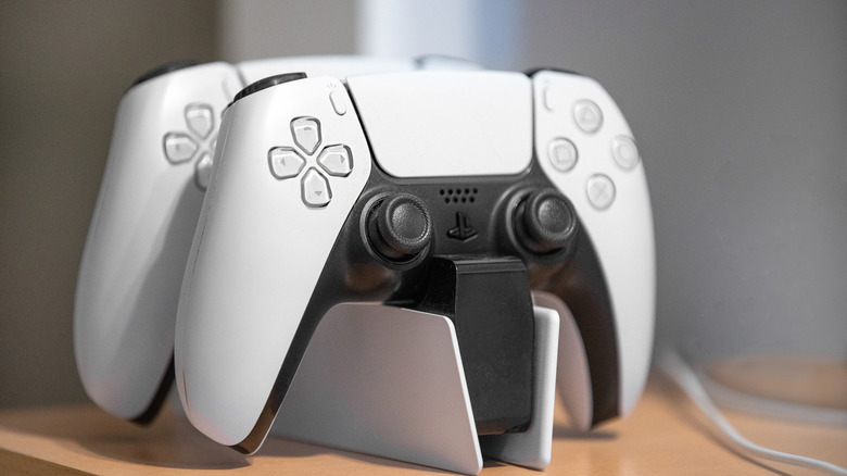 Two PS5 controllers sitting on a charging dock