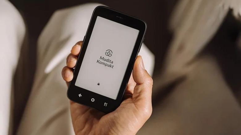 A person holding up the Mudita Kompakt E Ink phone in their hand.