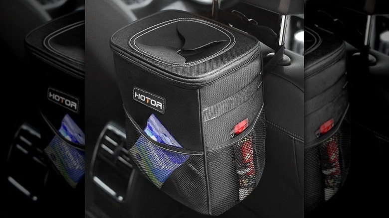 Trash bag loaded onto car's head rest containing trash