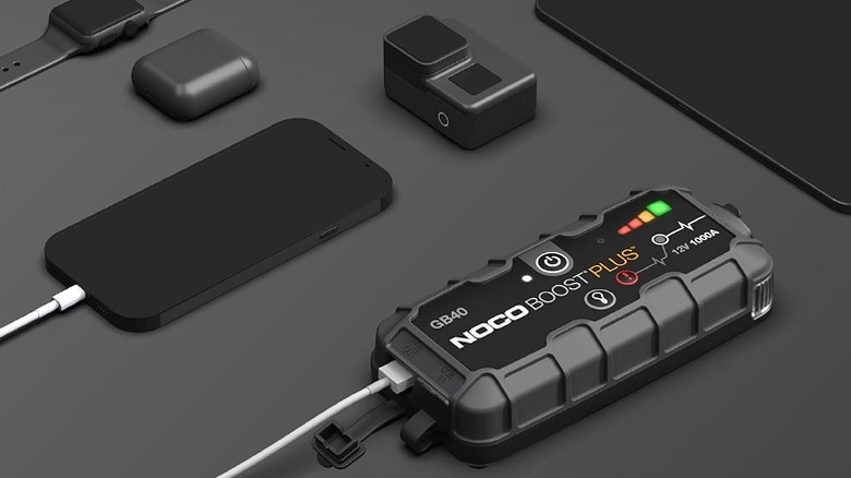 Jump starter connected to a smartphone with other gadgets on table