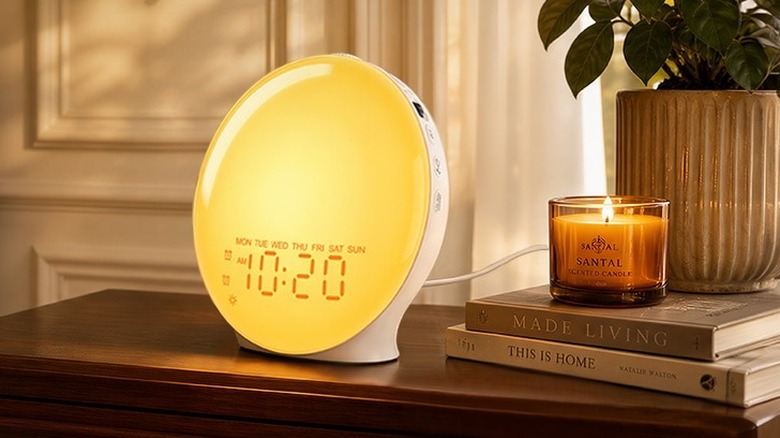 Jall Alarm Clock lit up on a nightstand next to a candle