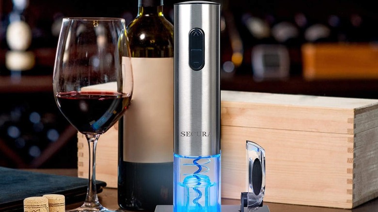 Secura Wine Bottle Opener next to an open glass and a wine bottle