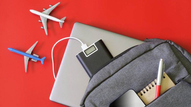 A gray backpack full of gadgets including a power bank and a laptop