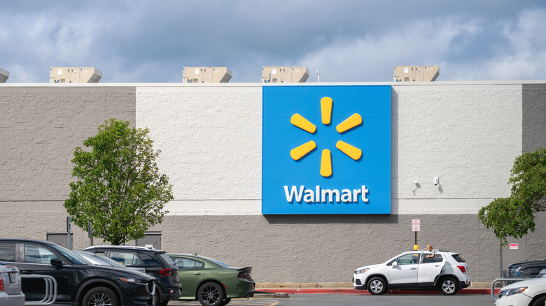The Walmart logo placed on a building with a parking lot in view.
