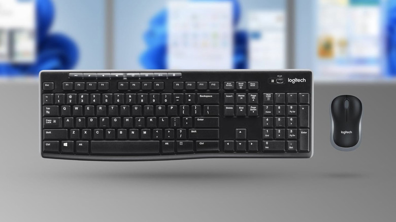 The Logitech wireless keyboard and mouse combo bundle on a blurred background of desktop displays.