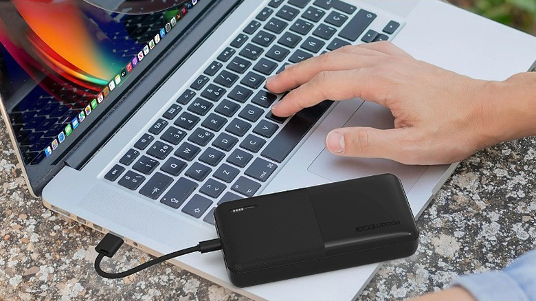 Black portable power bank charging a laptop