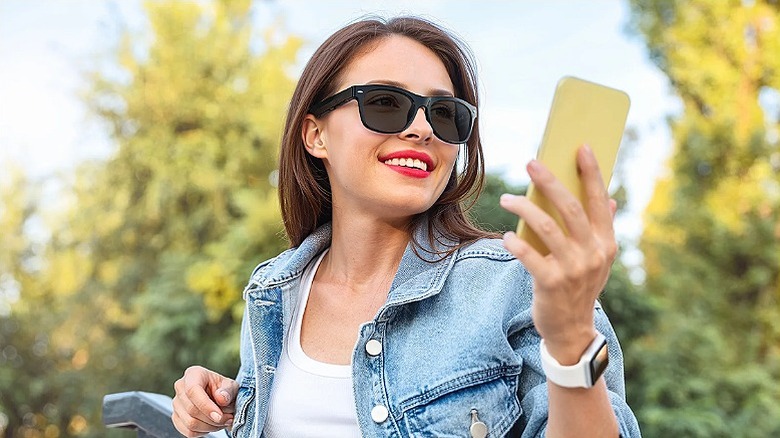 Woman wearing smart glasses and holding a smartphone