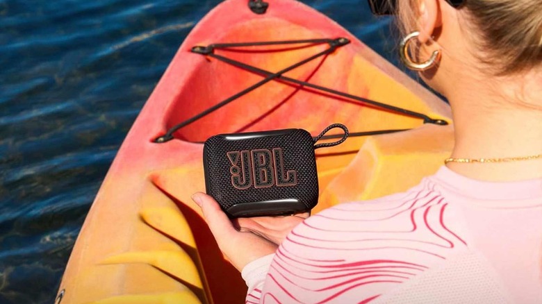 A woman in a boat holding a JBL Go 5