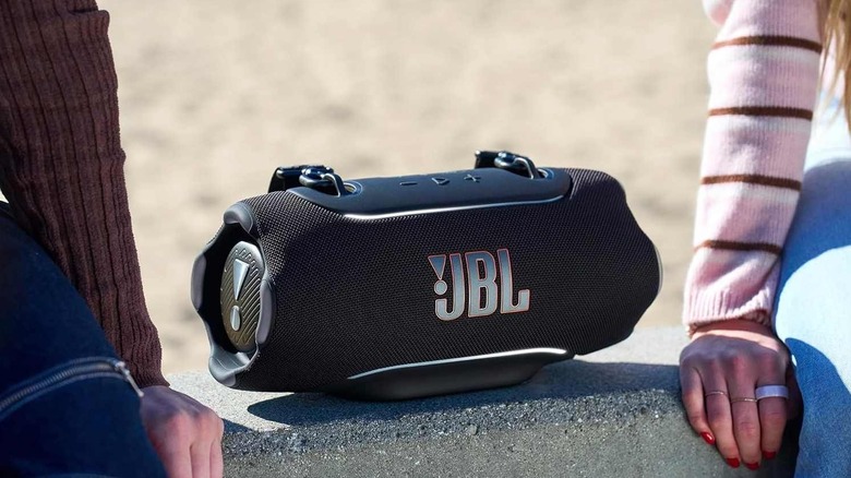 The JBL Xtreme 5 on a ledge between two people.