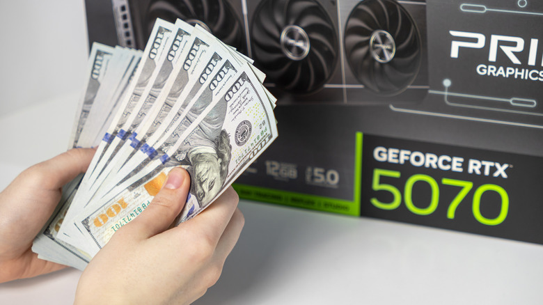 A person's hands count out cash to pay for an RTX 5070 graphics card.
