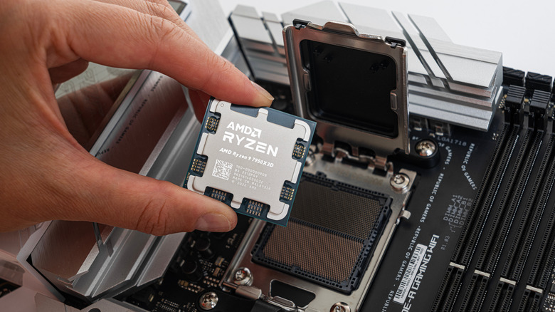 A hand about to install a Ryzen CPU on a motherboard.