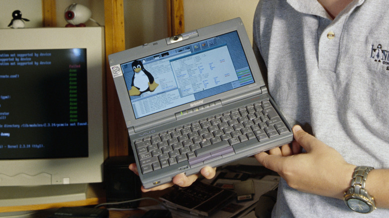 Linux Torvalds holds a laptop computer running Linux.