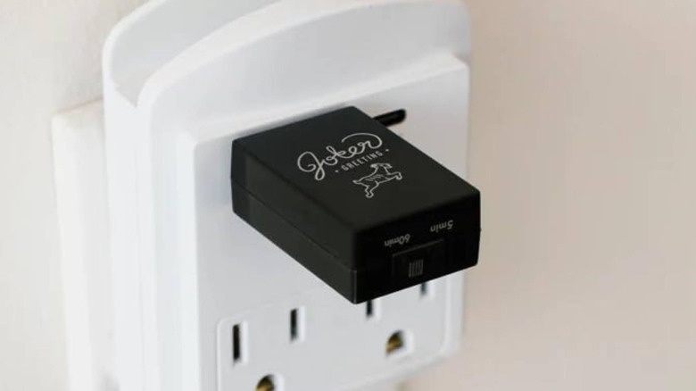 A black sound maker plugged into a white wall outlet