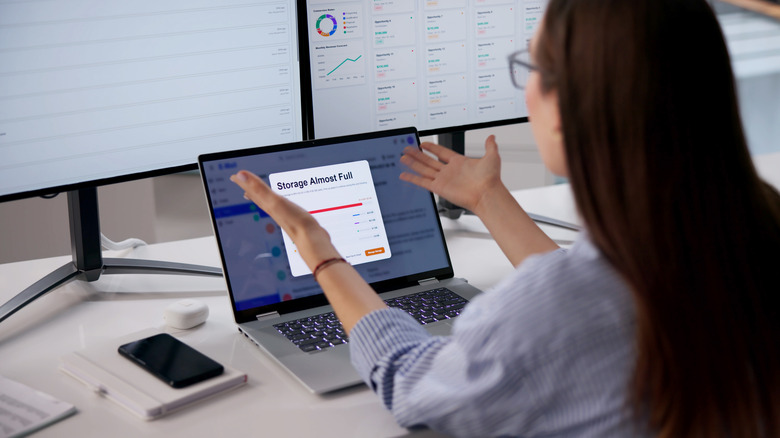 A woman receiving a notification on her laptop of nearly full storage.