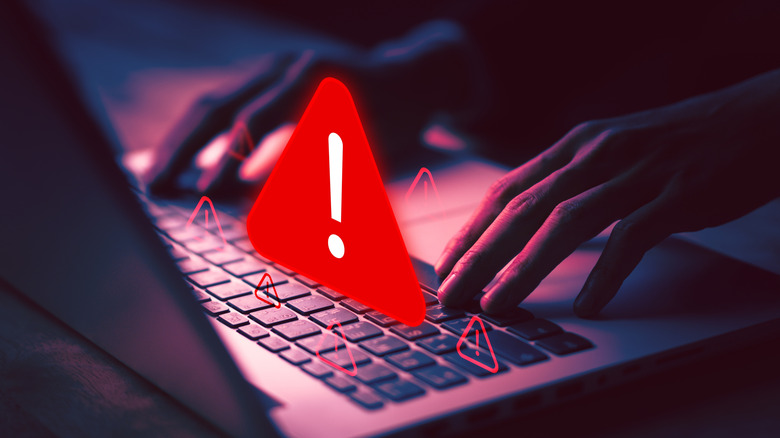 A red warning sign over a laptop while a person is using it.