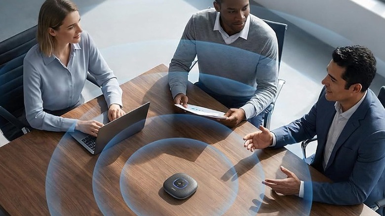 Two men and one woman sitting around a table with a speakerphone.