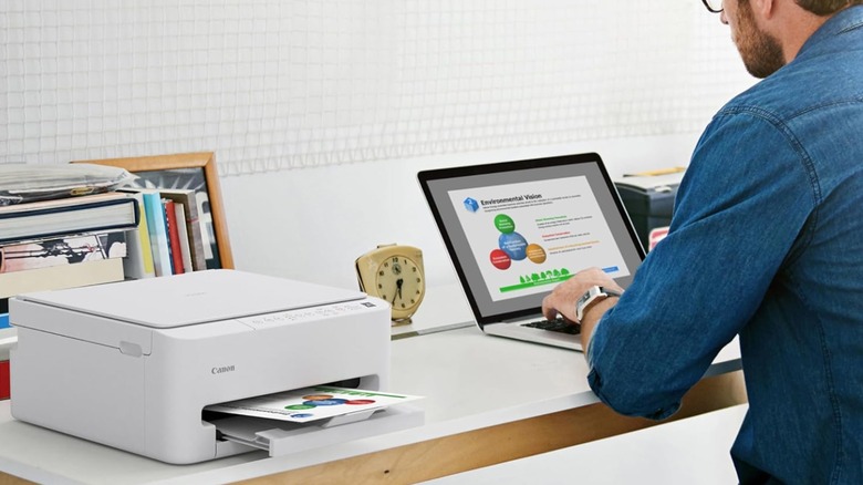 Man printing documents from a laptop using a printer.