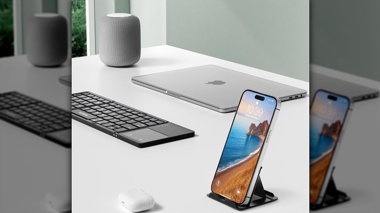 Smartphone on a stand beside a laptop and keybaord.