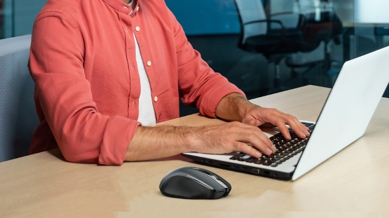 Man working on a laptop with a wireless mouse.