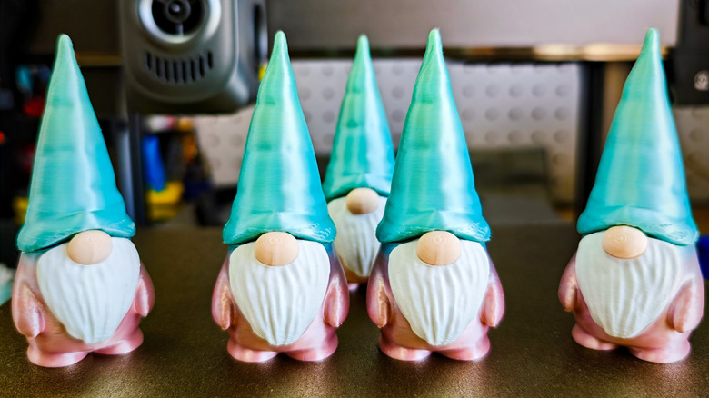 Multcolor 3D-printed gnomes stand around on a build plate.