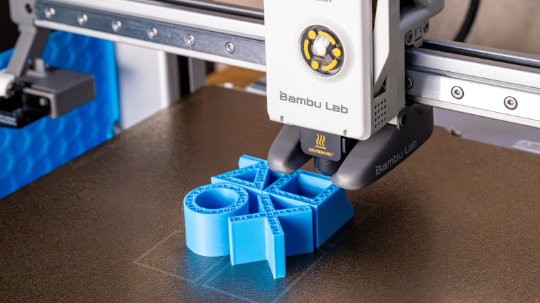 A 3D printer in the process of creating a model of the PlayStation button symbols.