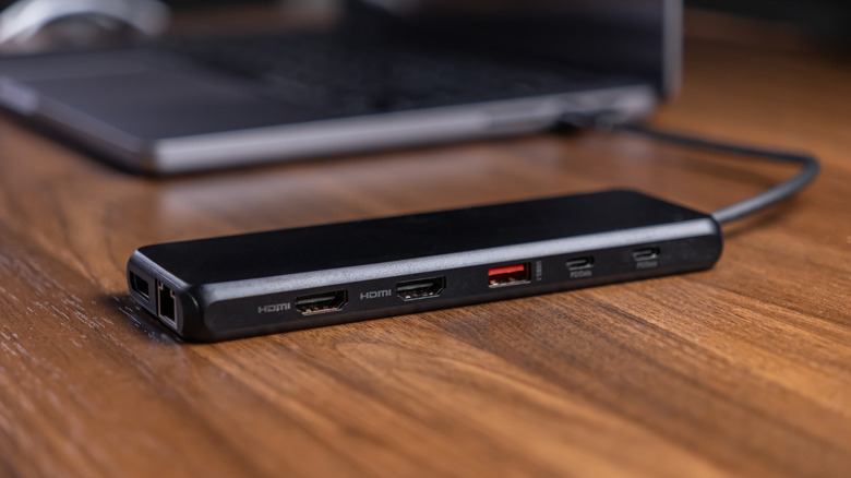 A docking station in the foreground is connected to a laptop in the background.