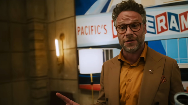 Seth Rogen as Matt Remick speaking at the front of an office during a meeting