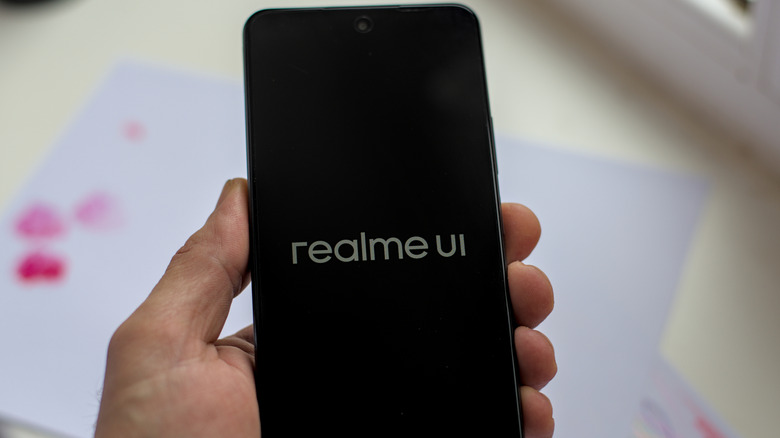 Person holding realme c71 phone showing realme ui logo
