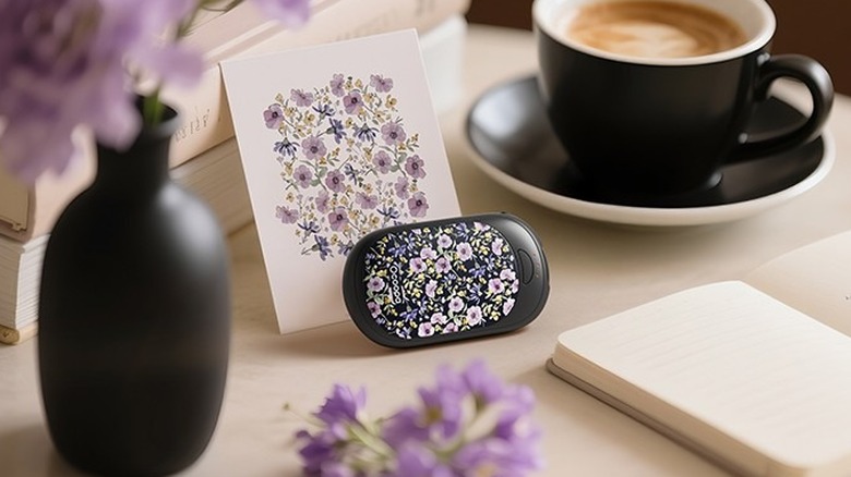 OCOOPA Magnetic Hand Warmers flanked by a coffee cup and a flower vase